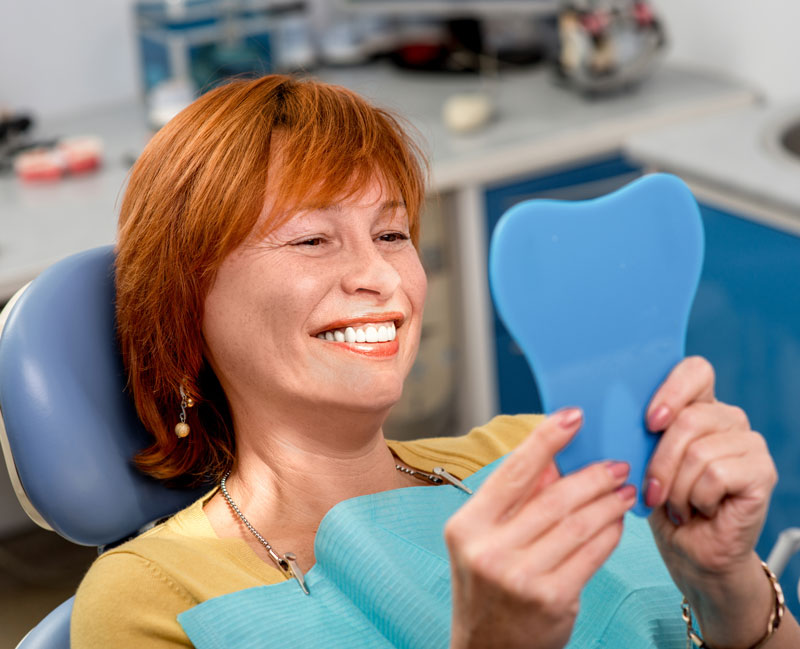 women inspecting new dentures